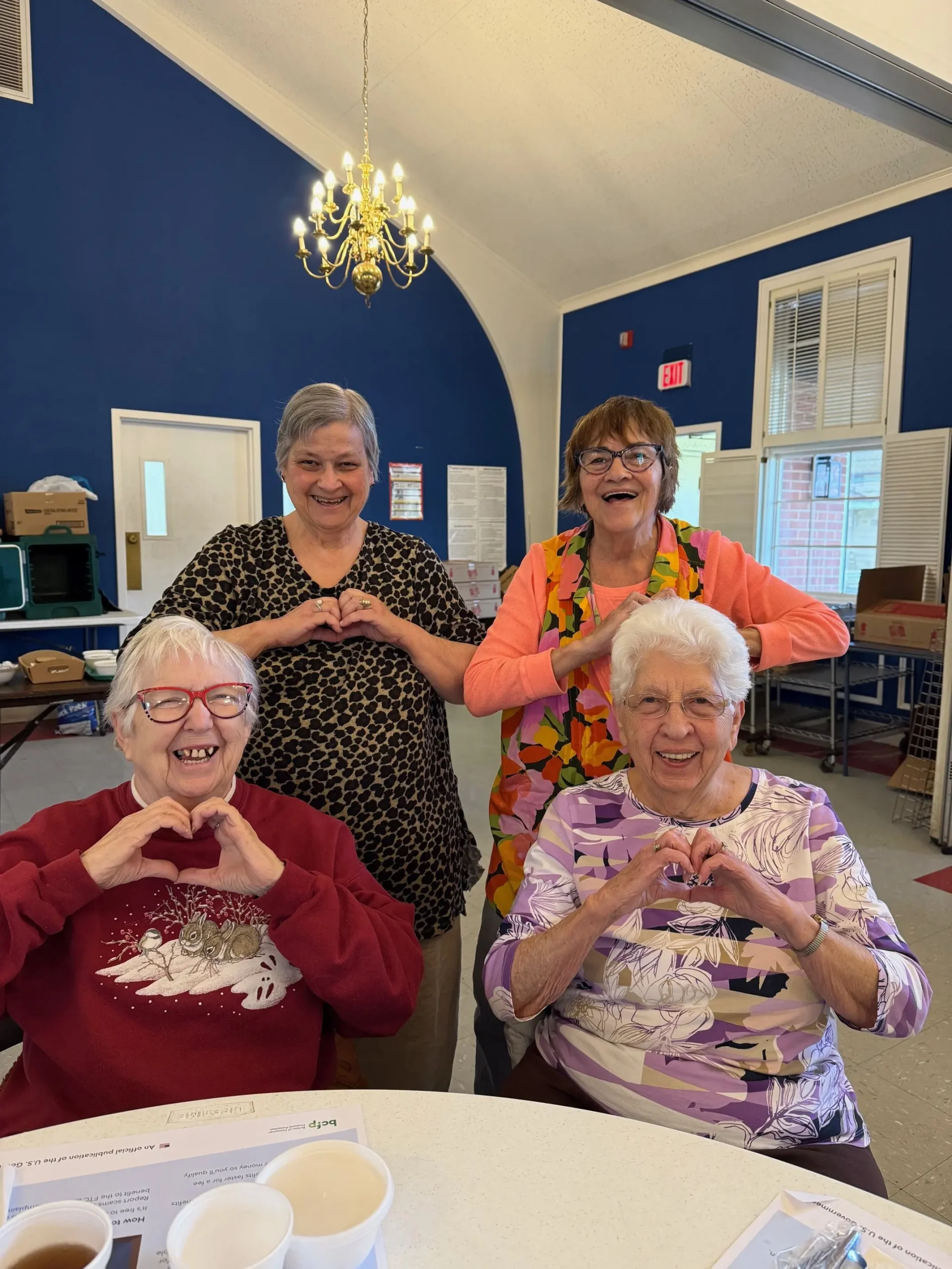 four women making a heart with their fingers