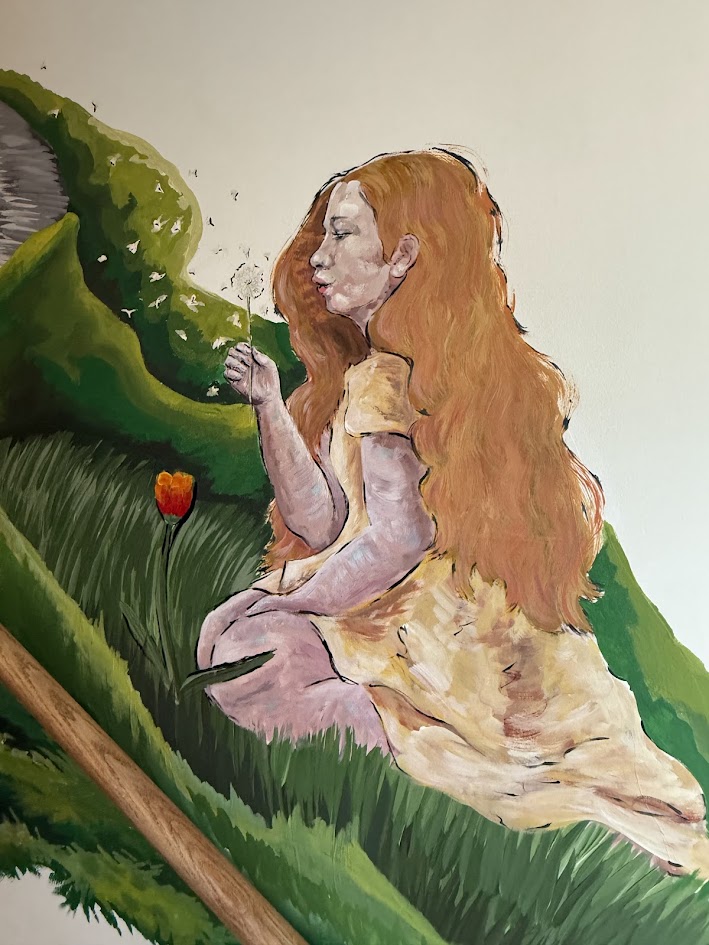 image of a mural with a young sitting on her knees blowing on a dandelion