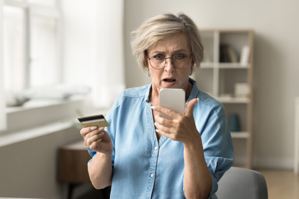 senior women looking worried holding a cell phone and credit card